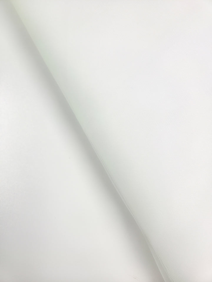 A close-up of Super Cheap Fabrics' Soft Tulle - White (150cm), draped diagonally, displays subtle shadows and a soft texture across its smooth surface, perfect for costumes or elegant bridal veils.