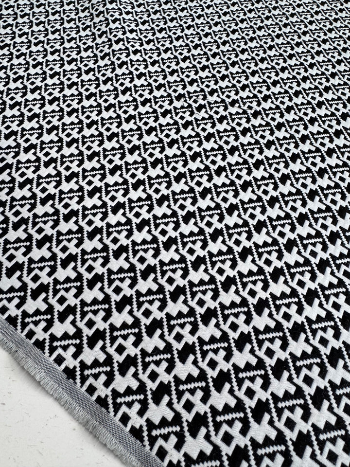 A close-up of Super Cheap Fabrics' Designer - Brushstrokes - Black & White rug (148cm) reveals its bold geometric pattern in durable 100% polyester 300GSM, with the edge visible, showcasing a striking modern style.