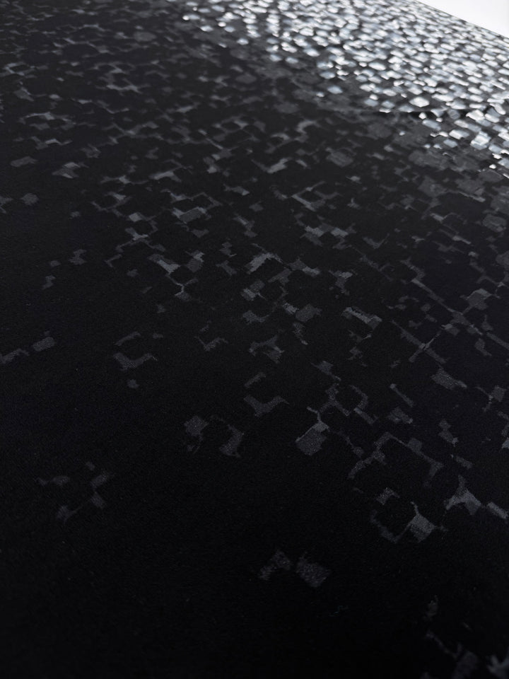 The Designer Lycra Panel - 90cm Panel by Super Cheap Fabrics features irregular, reflective geometric patterns becoming denser and brighter toward the top, creating a striking black-to-silver gradient on a 150cm wide fabric.