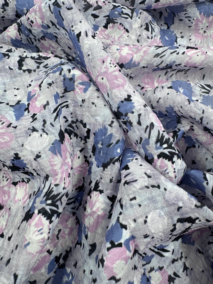 Close-up of crumpled Designer Jacquard - romi by Super Cheap Fabrics, featuring lightweight polyester with a floral pattern in blue, pink, and black on light gray. Abstract flowers and leaves create a soft texture perfect for multi-use applications. Width: 145cm.