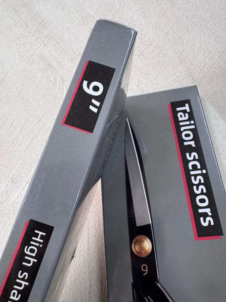 Two grey boxes on a light surface, one labeled "9'' High sha..." and the other "Tailor Scissors 9” Dressmaking Shears" by Super Cheap Fabrics, showing black shears with an ergonomic design, brass screw, and the number 9 on the blade.