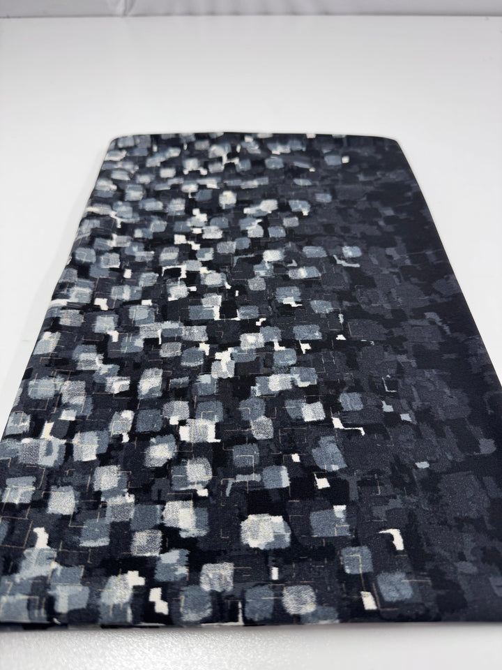 The Designer Lycra Panel - 90cm Panel by Super Cheap Fabrics features a black rectangular design with an abstract white and gray square pattern, displayed on a white surface.