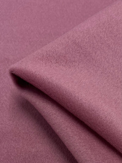 A close-up of Super Cheap Fabrics' Wool Cashmere in Dusty Rose (150cm) reveals a soft, folded wool material, reminiscent of luxurious outer coat textures, with a plush and cozy cashmere-like appearance.