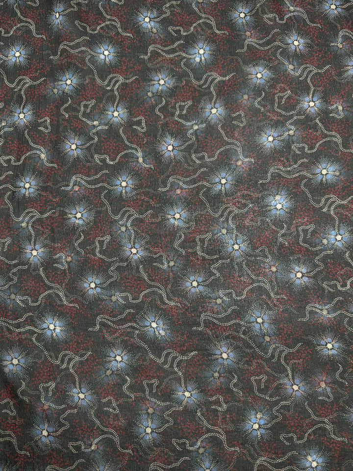 The Pure Printed Silk - Artisan - 140cm fabric by Super Cheap Fabrics features a dark green background adorned with intricate, swirling lines in red and white. The high-quality printed silk enhances the design, while small star-like motifs with blue centers are dispersed throughout, creating a visually textured and dynamic appearance perfect for high-end fashion.