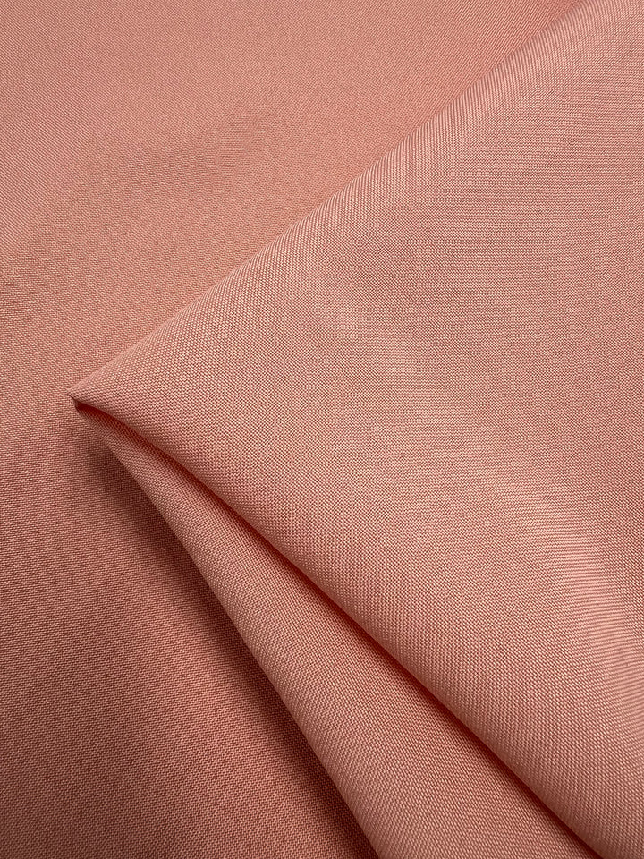 A close-up of Panama Suiting - Prairie Sunset by Super Cheap Fabrics, a 150cm wide, medium weight polyester fabric in light pink with a smooth, subtly textured surface and fine diagonal lines.
