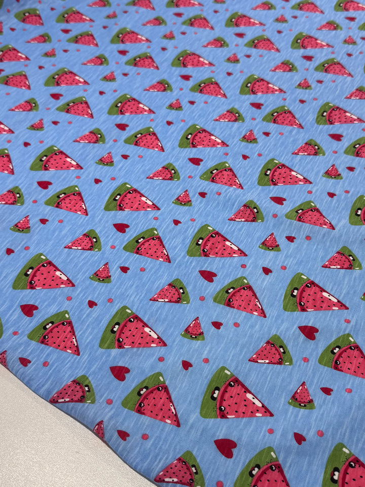 Super Cheap Fabrics' Printed Jersey - Sandia - 145cm features a blue background with cartoon watermelon slices and red hearts, plus a soft feel, two-way stretch, and medium weight for comfort.