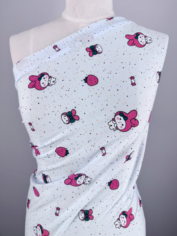 A mannequin is adorned with Super Cheap Fabrics' Printed Jersey - Melody, a medium-weight fabric featuring cute cartoon bunnies and strawberries with small red dots on a light background. Its two-way stretch offers versatility. Width: 140cm.