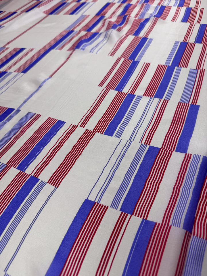 Experience the allure of luxury fashion with "Pure Silk - Mod Stripe - 140cm" by Super Cheap Fabrics, featuring a geometric grid of red and blue stripes on a white background.
