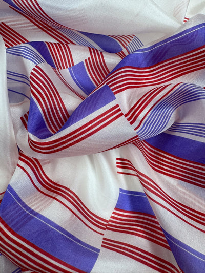 Discover Super Cheap Fabrics' Pure Silk - Mod Stripe - 140cm, a luxurious fabric with a wavy texture that showcases alternating red and blue stripes on a white background, perfect for high-end fashion attire.
