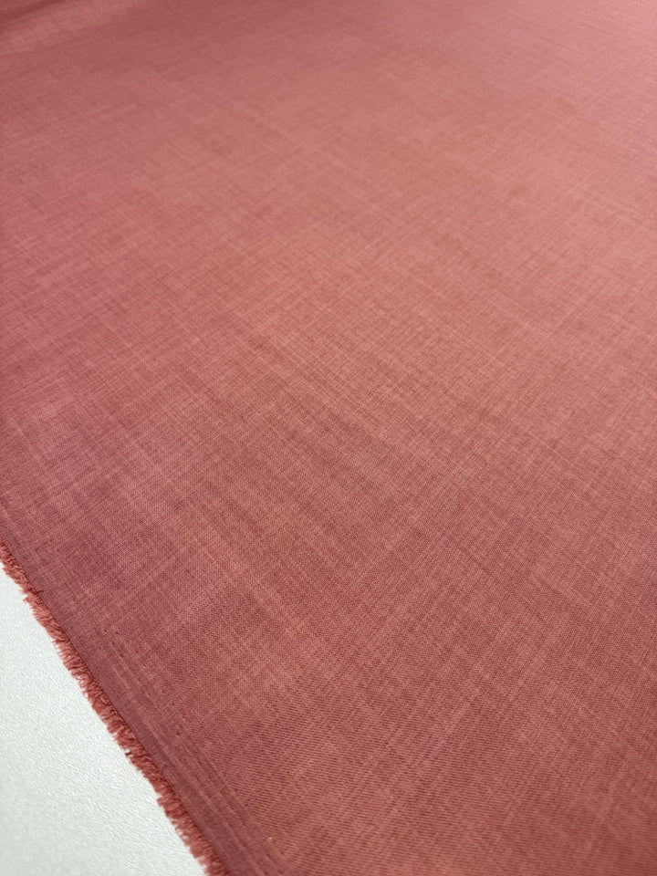A close-up of Super Cheap Fabrics' Twill Suiting - Terra Cotta (150cm) shows a soft, subtle diagonal weave and a slightly frayed edge on the left, highlighting the 100% polyester twill texture.