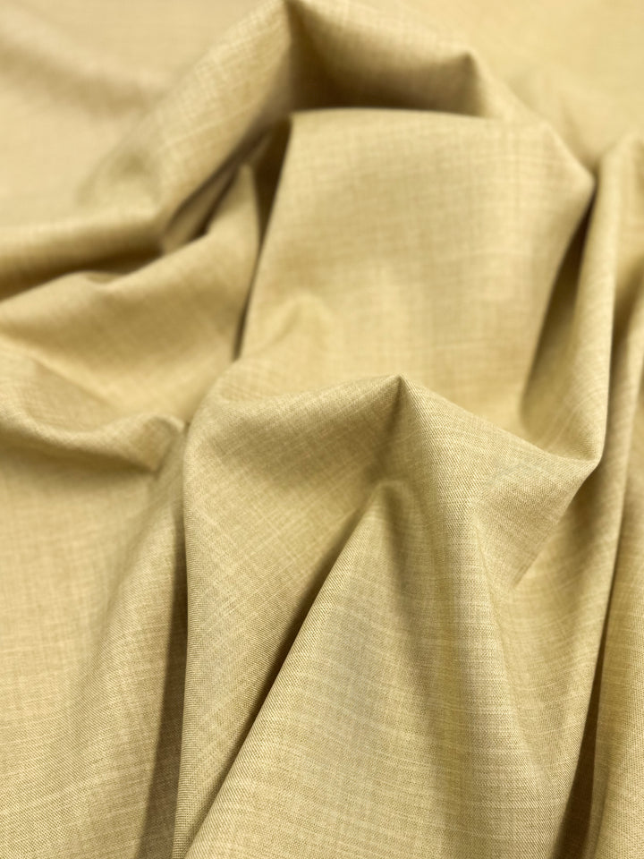 A close-up of Twill Suiting - Cocoon (150cm) by Super Cheap Fabrics showcases its beige textured pattern and soft diagonal weave with gentle folds—perfect for creating versatile, elegant attire.
