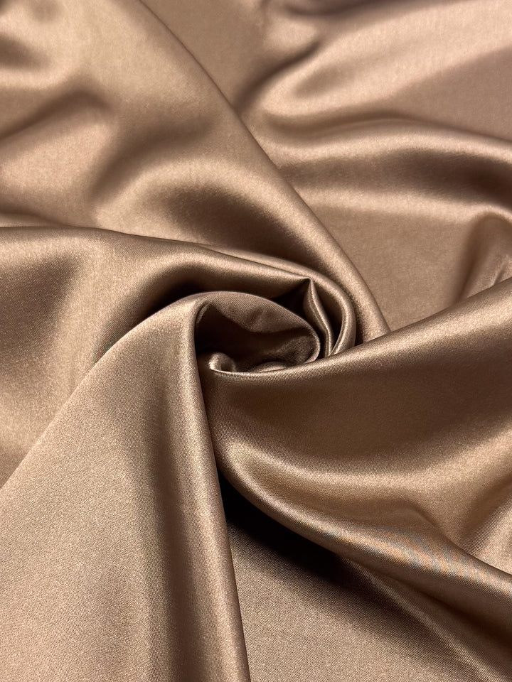 Close-up of Satin Deluxe - Chocolate Malt (150cm) by Super Cheap Fabrics, showcasing its smooth, glossy finish and silky texture in a light brown shade with soft folds and lustrous surface.