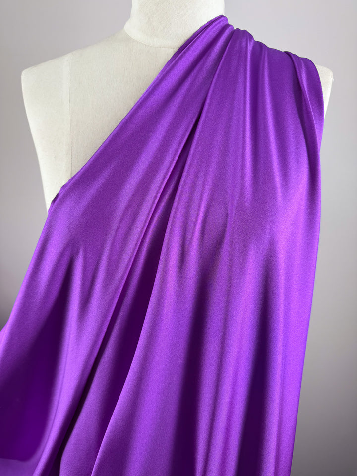 A white mannequin displays Super Cheap Fabrics' Nylon Lycra - Magenta - 154cm, draped over one shoulder to highlight its vibrant color, soft sheen, and subtle four-way stretch against a neutral background.