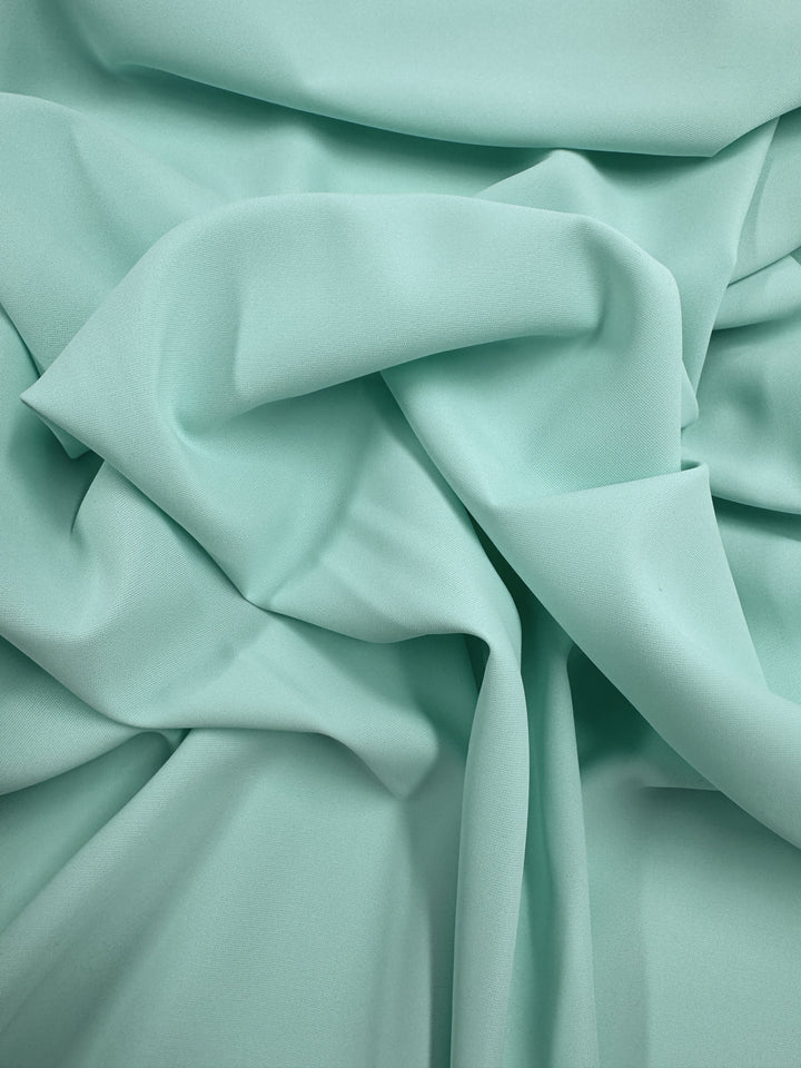 The Microfibre Suiting - Bay by Super Cheap Fabrics is a pale mint green, lightweight fabric with a smooth texture. It drapes loosely, forming gentle curves and soft, organic shapes—width: 150cm.