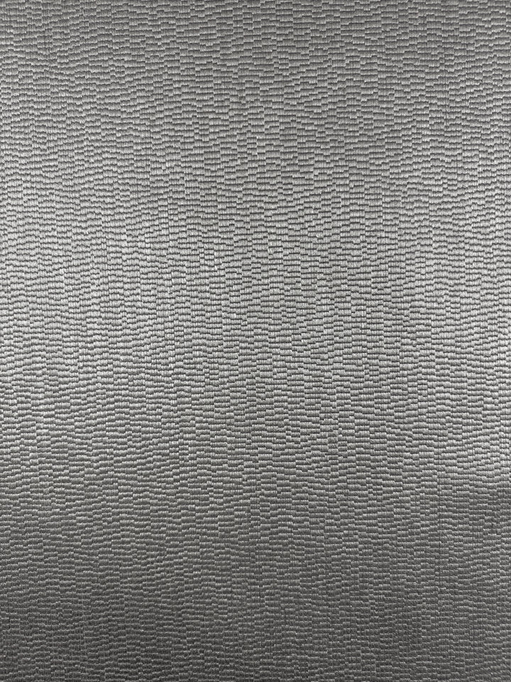 Close-up of Upholstery Jacquard - Oscar Putty (148cm) by Super Cheap Fabrics, featuring a metallic gray textured surface with a wavy rectangular pattern and a subtle sheen that highlights its heavyweight upholstery quality.
