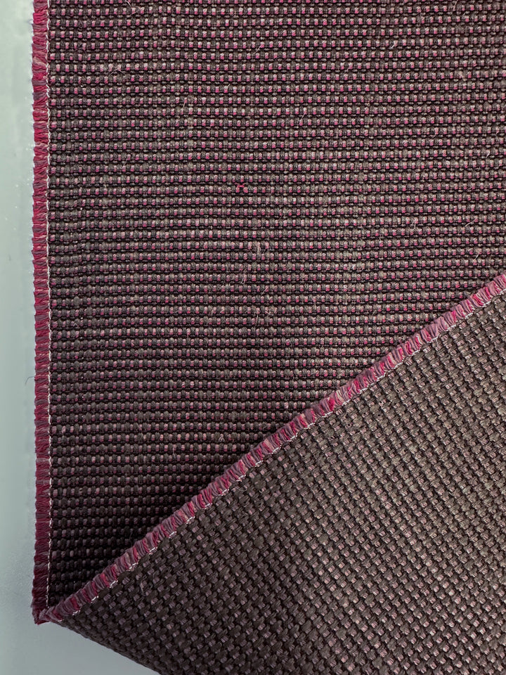 A close-up of Super Cheap Fabrics' Grid Upholstery - Yari 125 (147cm) shows its textured, dark burgundy heavy weight fabric with pink-edged threads, folded at the corner to reveal both front and back sides.
