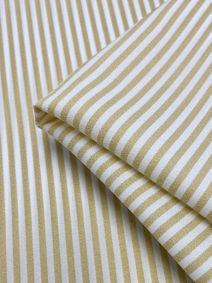 A close-up of Super Cheap Fabrics’ Striped Crepe - Raffia, 150cm wide, featuring beige and white vertical stripes and a smooth crepe texture—perfect for high fashion projects.