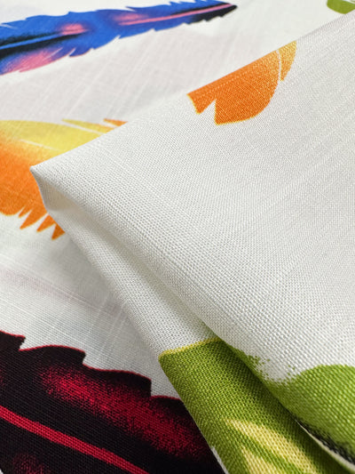 A close-up of Super Cheap Fabrics’ Bamboo Rayon - Feather White (150cm), showing its colorful feather pattern on a white base and lightweight woven texture—ideal for beginner sewing projects.