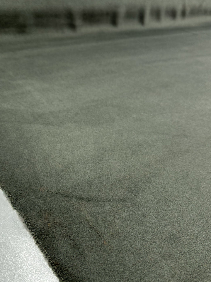 Close-up of Super Cheap Fabrics’ Wool Cashmere - Agave Green (150cm): smooth, suede-like surface with luxurious softness and subtle texture; a faint circular mark appears at center, with the top edge fading into shadow.