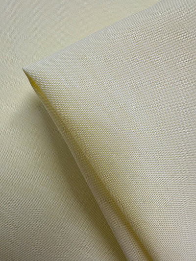 Close-up of Super Cheap Fabrics’ Oxford Cotton - Lemon (146cm) fabric, folded on a flat surface to highlight the detailed weave and texture of this cotton material.
