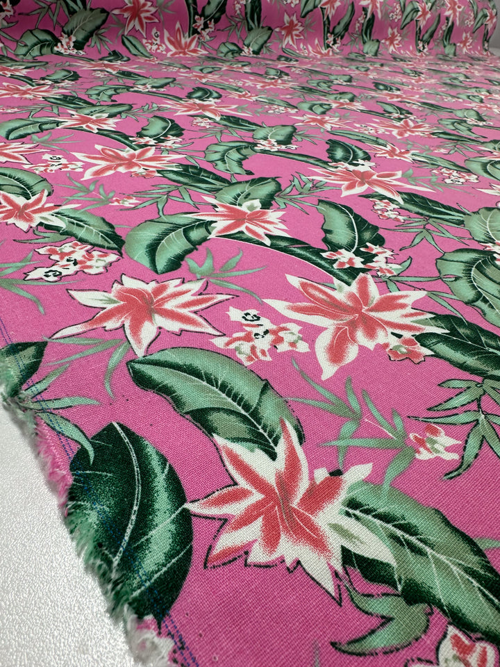 The Jungle Bloom Printed Linen Blend by Super Cheap Fabrics is a 140cm-wide fabric featuring a tropical floral pattern with large white and pink flowers and green leaves on a pink linen-cotton blend.