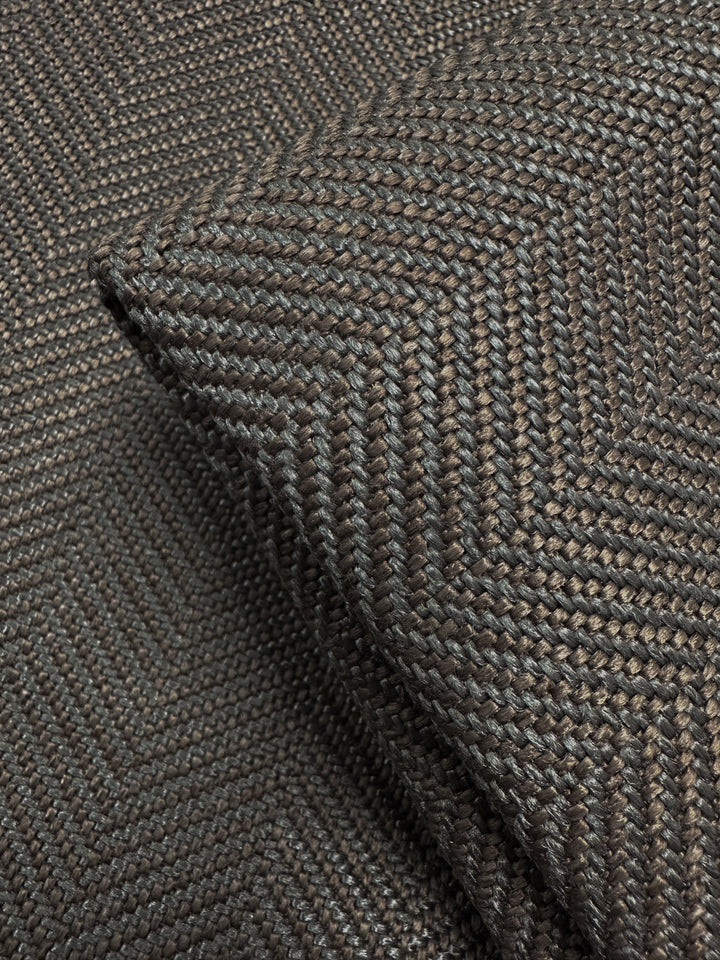 Close-up of Super Cheap Fabrics' Upholstery - Montpellier 15 - 145cm, a dark brown, textured woven fabric with a subtle chevron pattern. A folded corner highlights the intricate weave and quality of this premium Australian upholstery material.