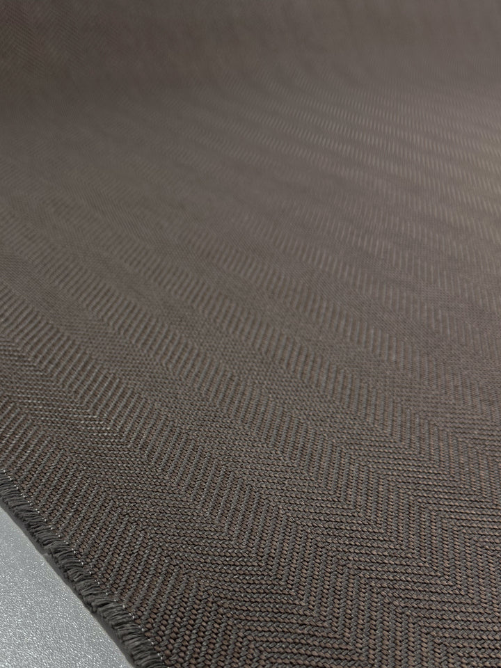 Close-up of Upholstery - Montpellier 15 - 145cm by Super Cheap Fabrics: a textured brown heavyweight upholstery fabric with a subtle herringbone pattern, highlighting its weave and edge stitching.