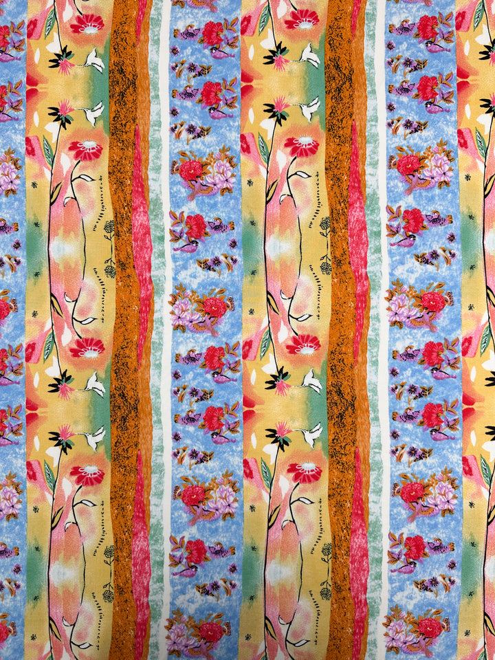 Designer Rayon - Wildframe - 145cm by Super Cheap Fabrics features vibrant vertical stripes with hand-drawn red flowers, green leaves, yellow shapes, and textured orange and blue bands, alternating with pink and purple floral clusters on blue.