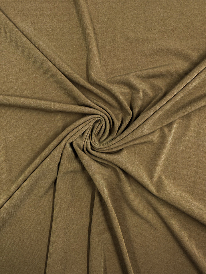 Super Cheap Fabrics' ITY Knit - Nuthatch (150cm) is an olive green, medium weight fabric with a smooth texture, draped in soft folds radiating from a central twisted swirl.