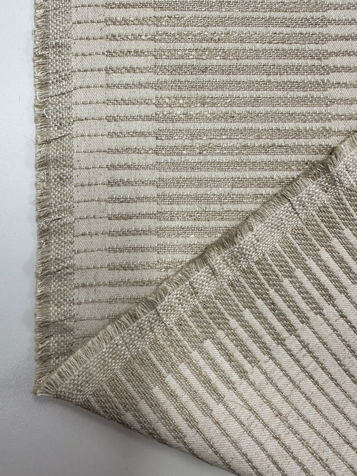 A close-up of Super Cheap Fabrics' Textured Jacquard Upholstery - Melmoth Stripe Nat (142cm), showing its striped, textured beige and light brown design with front and back sides visible, frayed edges, and a folded corner.
