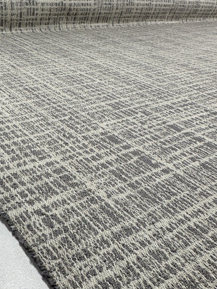 A close-up of Super Cheap Fabrics' Textured Weave Upholstery - Dexter 33 Dove (147cm), showing a large roll with a gray and beige woven pattern featuring subtle intersecting lines for an abstract design.
