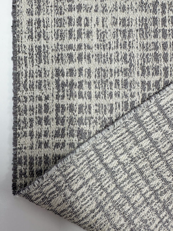 A close-up of Super Cheap Fabrics' Textured Weave Upholstery - Dexter 33 Dove (147cm), showcasing its premium Australian quality, gray and off-white grid-like texture, and both front and slightly turned-up back.