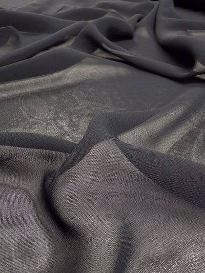 A close-up of Super Cheap Fabrics’ Single Georgette in Darkest Navy (143cm), a sheer fabric with soft folds and gentle creases, creates a textured, slightly shiny surface—ideal for floaty tops.