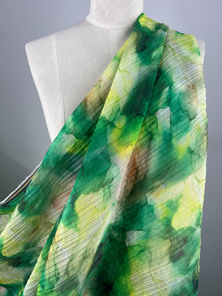 A mannequin draped in Super Cheap Fabrics' vibrant, multi-colored Textured Tencel - Mossy fabric, showcasing shades of green, yellow, blue, and white. This sustainable 140cm fabric features a crinkled texture and watercolor effect, creating a dynamic and flowing appearance with unmatched softness.