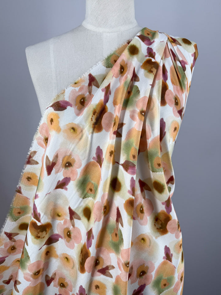 A white mannequin displays Super Cheap Fabrics’ Mercerised Rayon - Blushed Camellia (150cm), a soft, breathable fabric with a watercolor floral pattern in peach, green, yellow, and mauve.