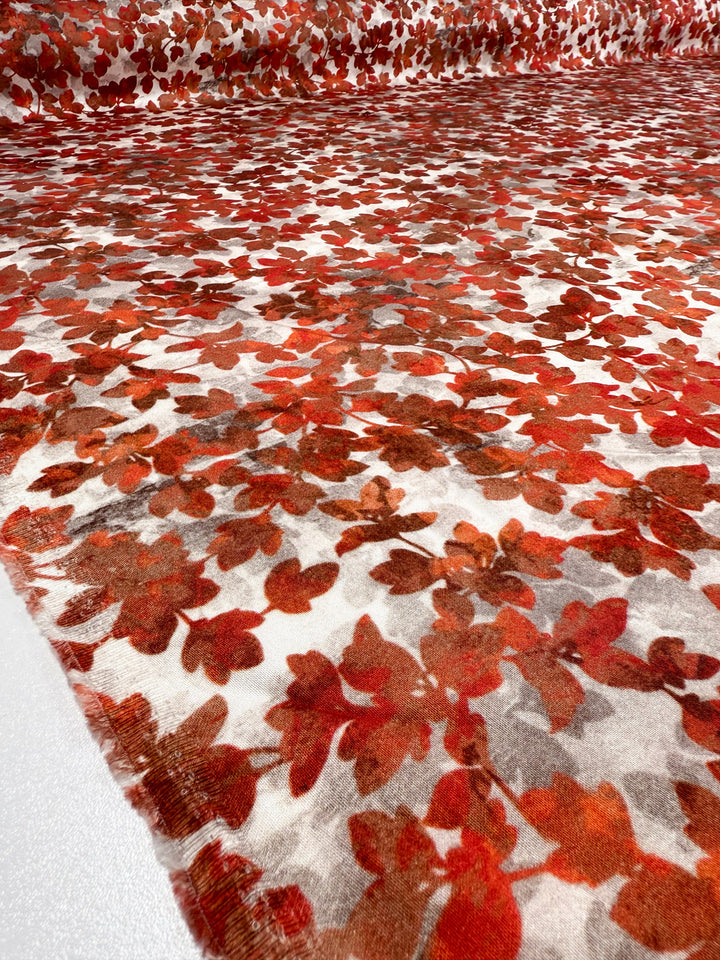 A close-up of Mercerised Rayon - Crimson Canopy by Super Cheap Fabrics, showing its lightweight, breathable fabric with a dense autumn leaf pattern in red, orange, and brown on white, spanning the full 150cm width.