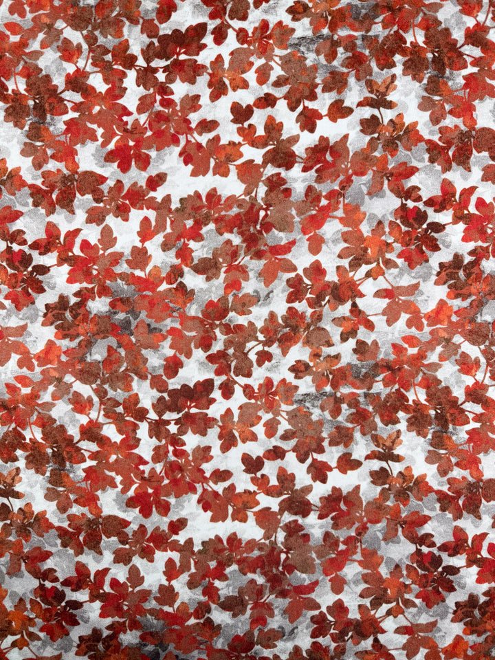Super Cheap Fabrics’ Mercerised Rayon - Crimson Canopy - 150cm features a dense seamless pattern of red, orange, and brown autumn leaves on a light textured background, ideal for breathable seasonal designs.