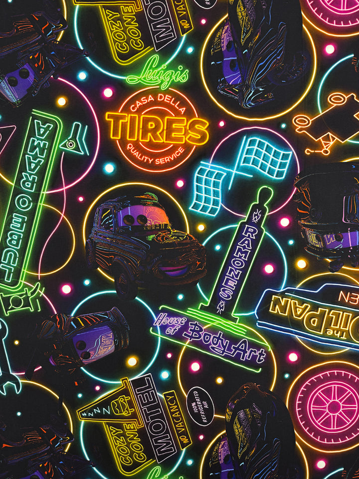 Designer Rayon - After Dark (140cm) from Super Cheap Fabrics features neon signs, racecars, Luigi’s Casa Della Tires, and checkered flags from "Cars" on a vibrant black background—ideal for fans of bold prints.