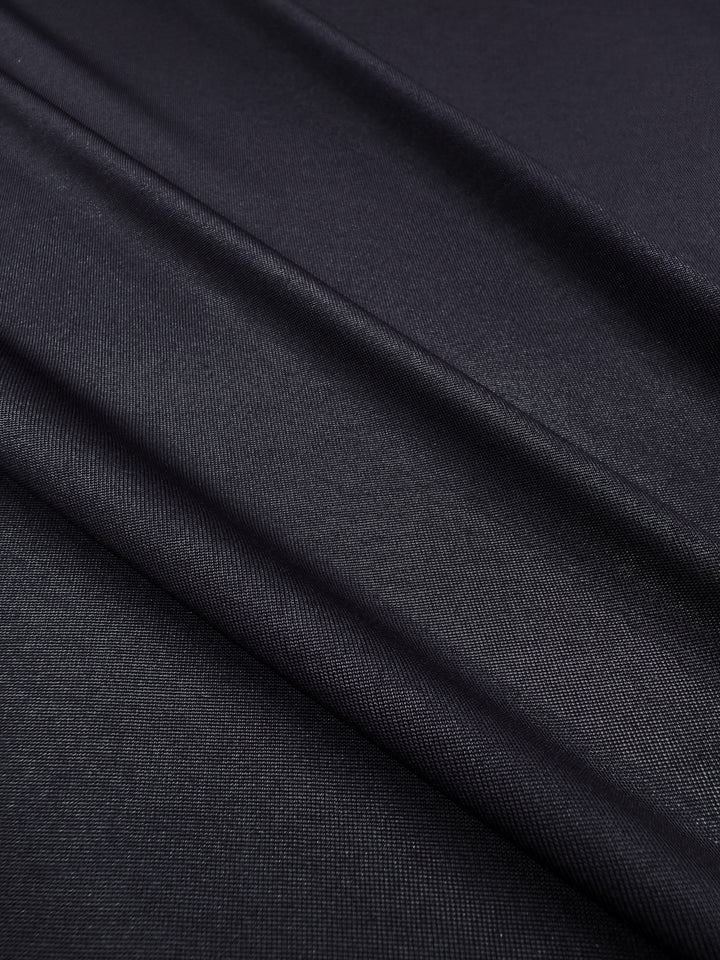 Close-up of Super Cheap Fabrics' Knit Lining in Dark Navy (160cm), featuring a subtle sheen and gentle diagonal folds. The fine, tightly woven polyester fabric creates a sleek, elegant look.