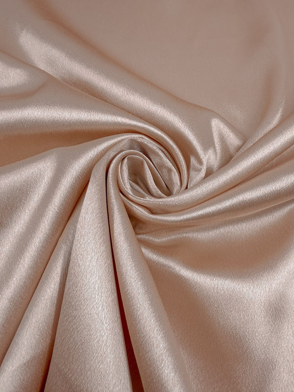 A close-up of Super Cheap Fabrics' Satin Back Crepe in Cream Tan (150cm), showing its smooth, shiny texture arranged in gentle folds with a spiral swirl at the center.