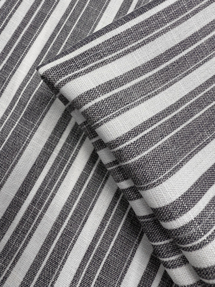 Close-up of two overlapping pieces of Super Cheap Fabrics' Linen Blend - Linen Stripe (150cm), featuring grey-white fabric with black and white horizontal and vertical stripes. The lightweight, woven texture enhances the design.