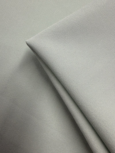 Close-up of Super Cheap Fabrics’ Liquid Twill - Murmur (150cm) in light gray. Medium weight twill with a fine, smooth texture; two pieces layered, one neatly folded on top, highlighting subtle shadows and crisp lines.