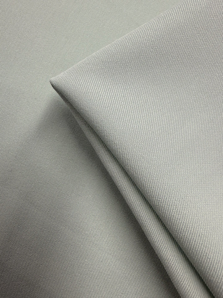 Close-up of Super Cheap Fabrics’ Liquid Twill - Murmur (150cm) in light gray. Medium weight twill with a fine, smooth texture; two pieces layered, one neatly folded on top, highlighting subtle shadows and crisp lines.