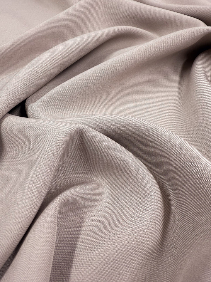 Close-up of Liquid Twill - Goat by Super Cheap Fabrics, a light taupe 150cm suiting fabric featuring a smooth texture, soft drape, fluidity, and subtle sheen—showcasing the classic qualities of fine polyester twill.