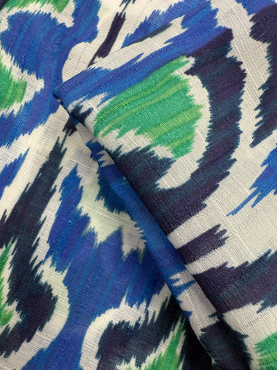 A close-up of Textured Designer Cotton - Tribal Sea by Super Cheap Fabrics, featuring a lightweight, folded 145cm cotton with an abstract ikat-style pattern in blue, green, white, and black—ideal for luxury sewing projects.
