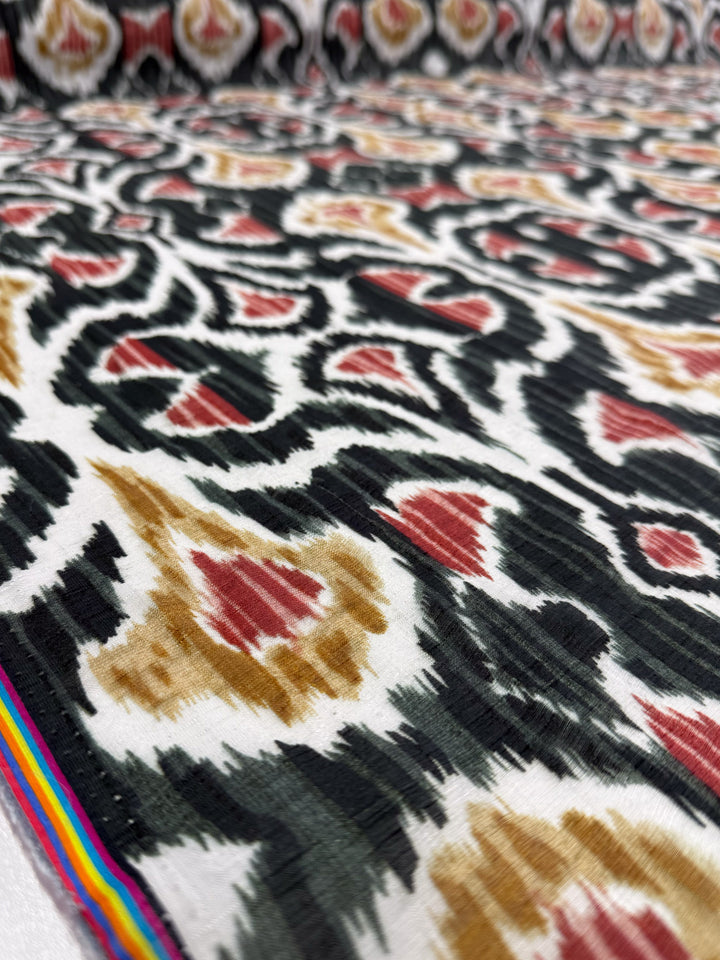 Close-up of Super Cheap Fabrics' Spice Loom Textured Designer Cotton (150cm): features abstract black, red, and yellow patterns on white with a thin multicolored striped edge.