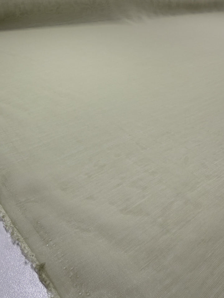 A close-up of Super Cheap Fabrics' Designer Voile - White Jade (150cm) shows its soft, slightly textured surface in light beige, laid flat with minimal fraying along the edge.