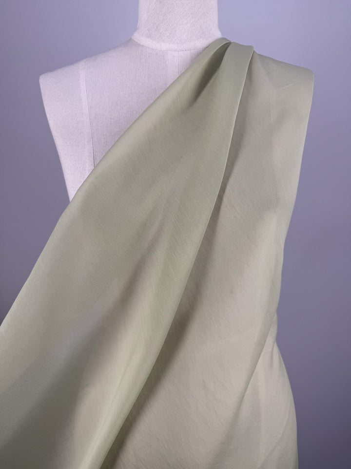 Super Cheap Fabrics' Designer Voile - White Jade (150cm) is draped diagonally over a white dress form, showcasing its sheer, lightweight texture and creating a soft, elegant look against a plain background.