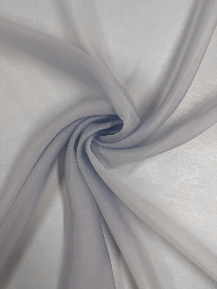 Designer Voile - Skywriting - 150cm by Super Cheap Fabrics features artistically gathered, twisted light gray fabric in a spiral pattern. Soft, translucent, and lightweight, it drapes smoothly with gentle folds.
