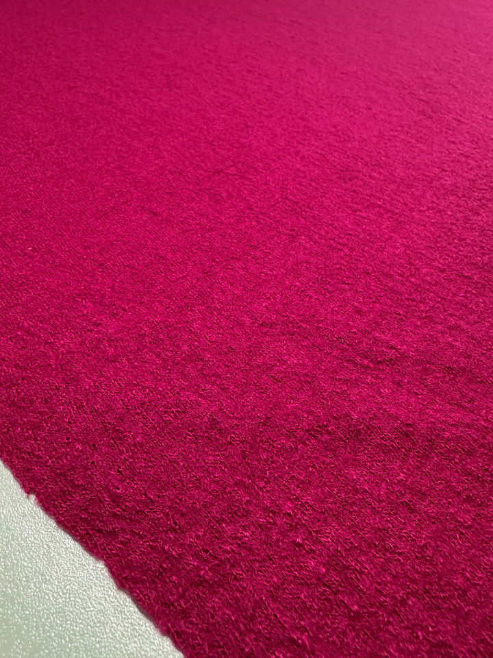 Close-up of Super Cheap Fabrics' Boiled Wool - Vivacious - 145cm, showcasing vibrant pink heavy weight wool with a rough, detailed texture highlighted by the lighting.